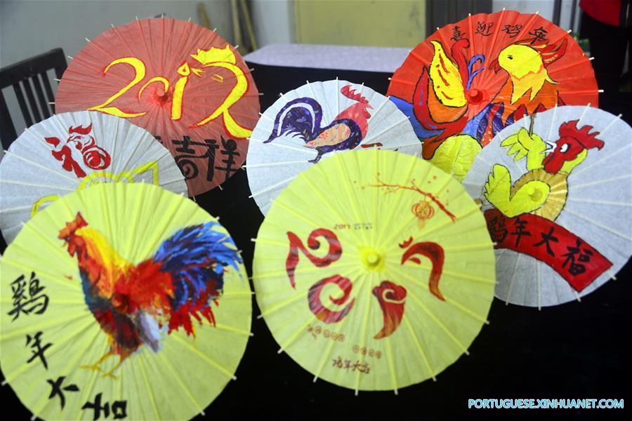 Estudantes internacionais pintam temas de galo em sombrinhas de papel chinesas