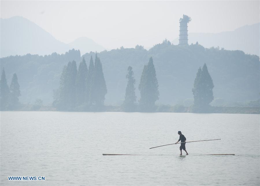 Cidad?o de Hangzhou atravessa rio Xin'an com duas canas de bambu