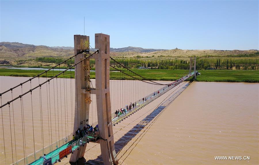 Turistas caminham em ponte de vidro sobre o rio Amarelo