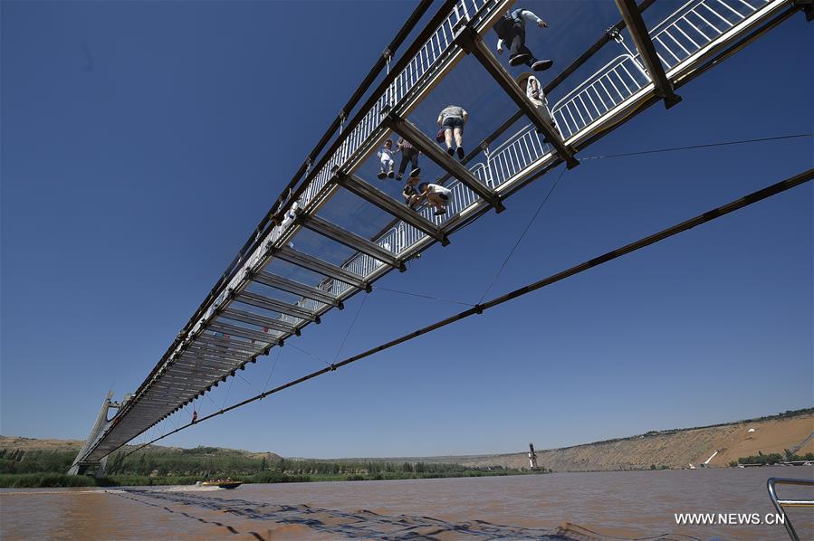 Turistas caminham em ponte de vidro sobre o rio Amarelo