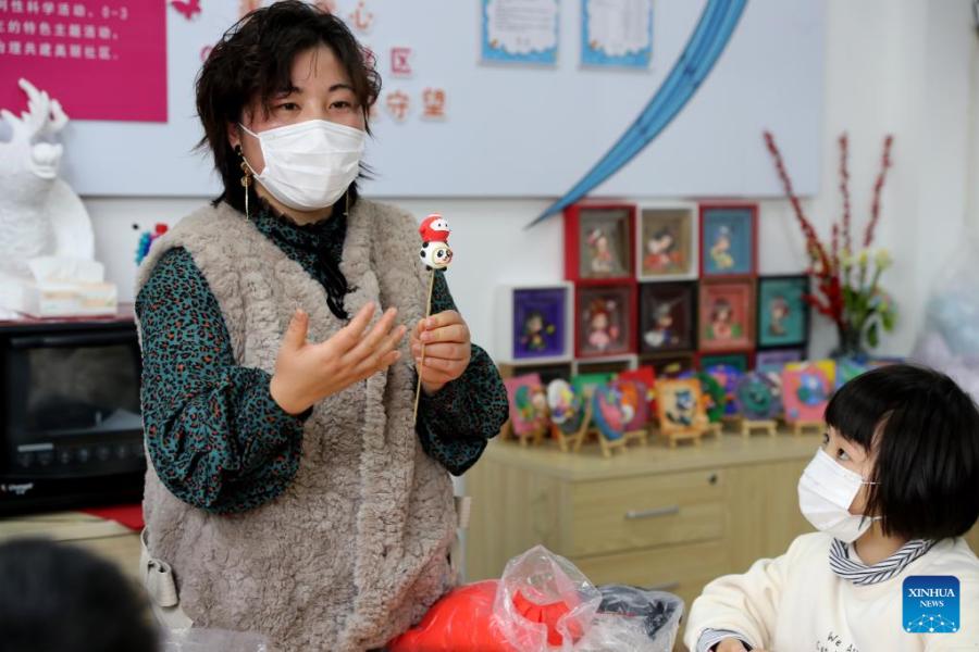 Crian?as fazem Bing Dwen Dwen com argila colorida em Shanghai